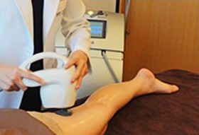 흰 가운 의료진 손이 다리에 흰 장비를 대는 장면